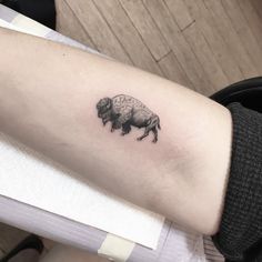 a small bison tattoo on the left inner arm and lower arm, it is black and white