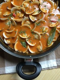 a pan filled with clams and sauce on top of a table