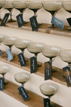 there are many wine glasses lined up on the shelf with tags attached to them,