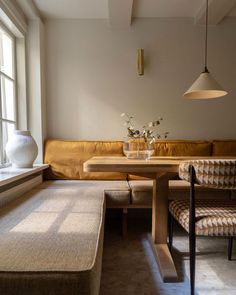 a living room filled with furniture next to a window and a vase on top of a table