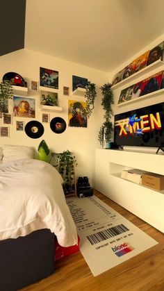 a bed sitting in a bedroom next to a wall with pictures on it and a tv