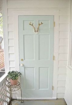 a white door with deer antlers on it and some plants in the window sill