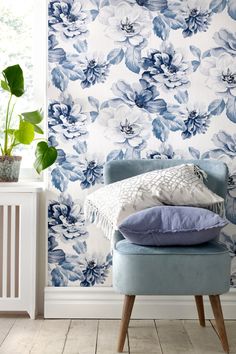 a blue chair sitting in front of a wall with flowers on it