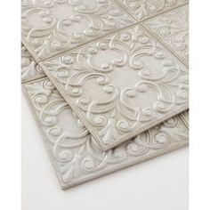 two white tile tiles on top of each other, one with an intricate design in the middle