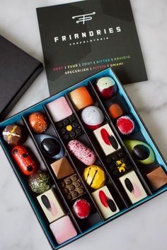 an assortment of different types of candies in a blue box on a marble surface