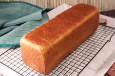 a loaf of bread sitting on top of a cooling rack next to a blue towel