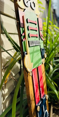 a wooden sign with numbers on it sitting in front of a house next to plants