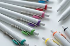 several pens are lined up in a row on a white surface, with one pen sticking out from the top