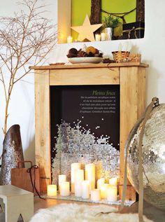 candles are lit in front of a mirror on a mantle next to a silver ball