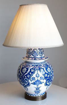 a blue and white vase with a lamp on it's side sitting on a table