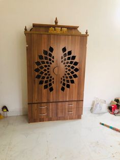 a wooden cabinet sitting on top of a white tile floor next to a wall with an intricate design