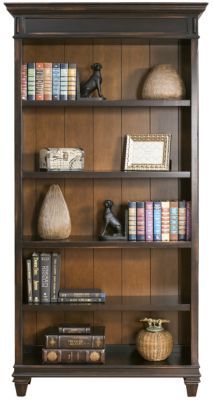 a book shelf with many books on top of it and two vases next to it