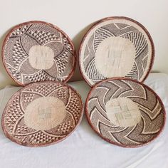 four woven baskets sitting on top of a bed