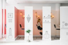 a woman is sitting in a room with pink walls and white columns that have drawings on them