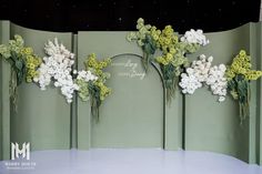 flowers are arranged on the wall in front of a stage set for a wedding ceremony