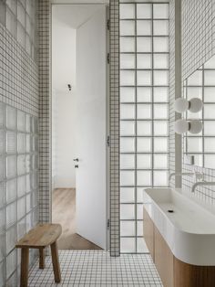 a bathroom with white tile and wood accents on the walls, along with a wooden bench