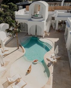 an aerial view of a house with a swimming pool and lounge chairs in the foreground