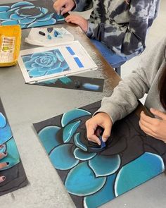 two girls are working on some artwork at a table