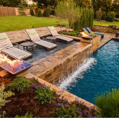 an outdoor pool with lounge chairs next to it and a waterfall running down the side