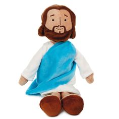 a stuffed jesus doll with a blue blanket on it's chest and feet, sitting down