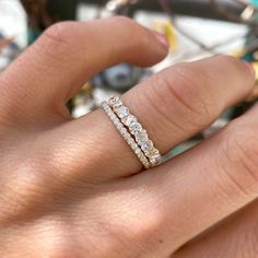 a woman's hand with a diamond ring on top of her finger and an engagement band in the middle