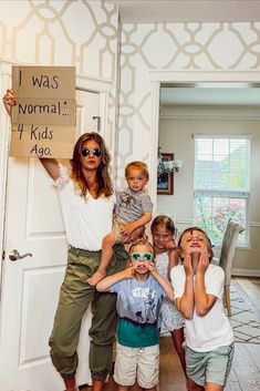 a group of children standing in front of a door with a sign that says i was normal, my kids ago