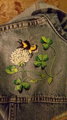 the back of a pair of jeans with embroidered flowers and butterflies on them, sitting on a table