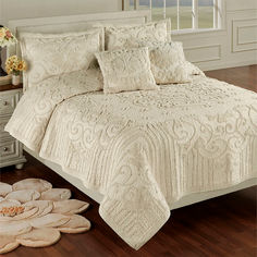 a bed with white bedspread and pillows on top of it in a room