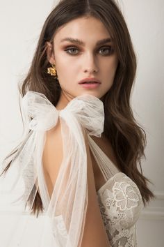 a woman with long hair wearing a white dress and gold earring on her head