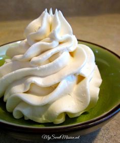 a green plate topped with whipped cream on top of a table