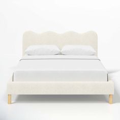 a white bed with two pillows on top of it