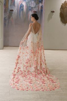 a woman standing in front of a painting wearing a dress with pink flowers on it