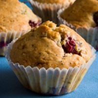 muffins with cranberry filling sitting on a blue tablecloth next to other muffins