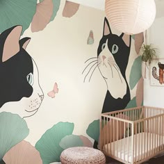 a baby's room with a cat mural on the wall and a crib