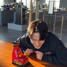 a woman is playing with a toy train on the table in front of her and smiling