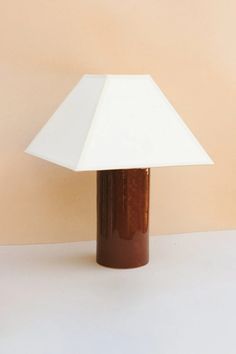 a brown and white lamp sitting on top of a table next to a beige wall