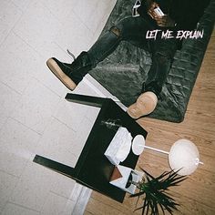 a man sitting on top of a wooden floor next to a black table and chair