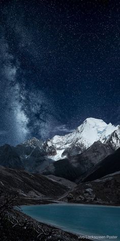 the night sky is filled with stars and clouds above a snowy mountain range, as seen from an alpine lake