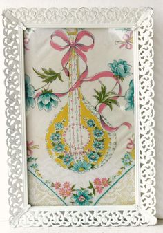 an ornate white frame with pink and blue flowers on the side, holding a ribbon