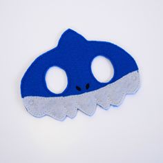 a blue and white felt mask with holes in the middle on a white surface,