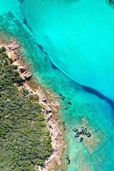 an aerial view of the ocean with blue water and green land in the foreground