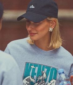 a blonde woman wearing a hat and blue shirt is holding a water bottle in her hand