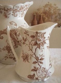 two white and brown vases sitting on top of a table