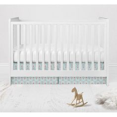 a white crib with a wooden rocking horse next to it and a rug on the floor