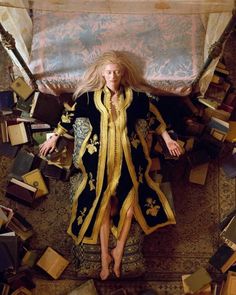 a woman laying on top of a pile of books in a room filled with boxes