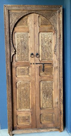 an old wooden door with intricate carvings on the front and side doors, in blue wall