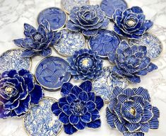 blue and white ceramic flowers are arranged on a marble countertop, with gold accents