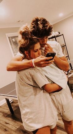 two people hugging each other while looking at a cell phone