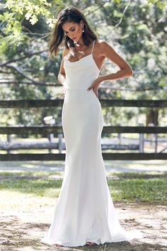 a woman in a white dress posing for the camera with her hands on her hips