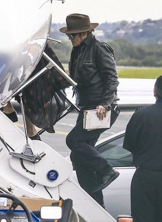 a man in a hat and sunglasses is getting out of an airplane